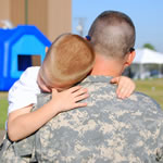 A servicemember holds his young son.