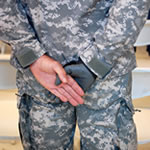 A servicemember crosses his hands behind him.