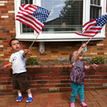 Two small children wave American flags.